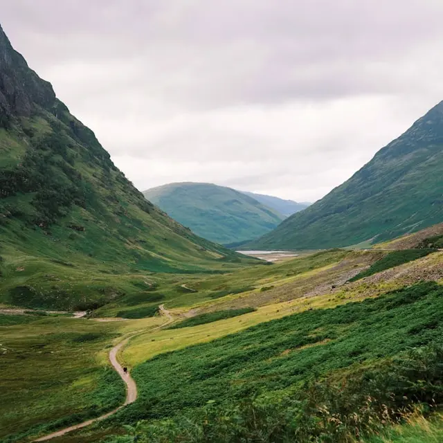 Scenic valley with a curving trail between lush green mountains.